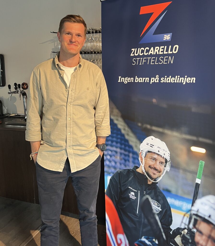 Lars stående ved siden av roll up av Zuccarellostiftelsen og Mats Zuccarello